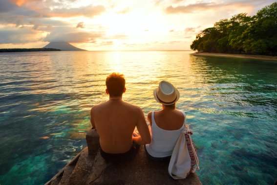 Romantic couple on the beach at colorful sunset on background