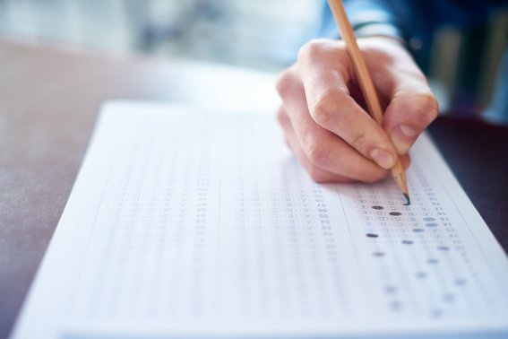 Hand of male student filling out test answer sheet