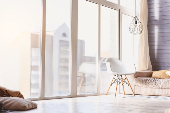 Relaxing view from window in cozy living room with modern interior. Chair near sofa on floor