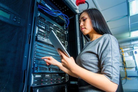 Young engineer businesswoman with tablet in network server room