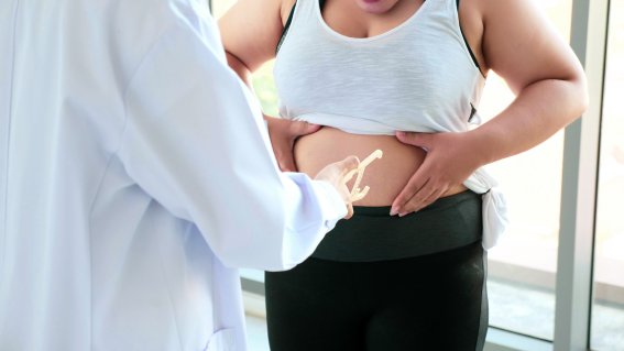 Chubby woman touching belly at the hospital room.