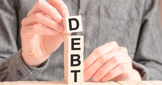 wooden cube with the letter from the word debt